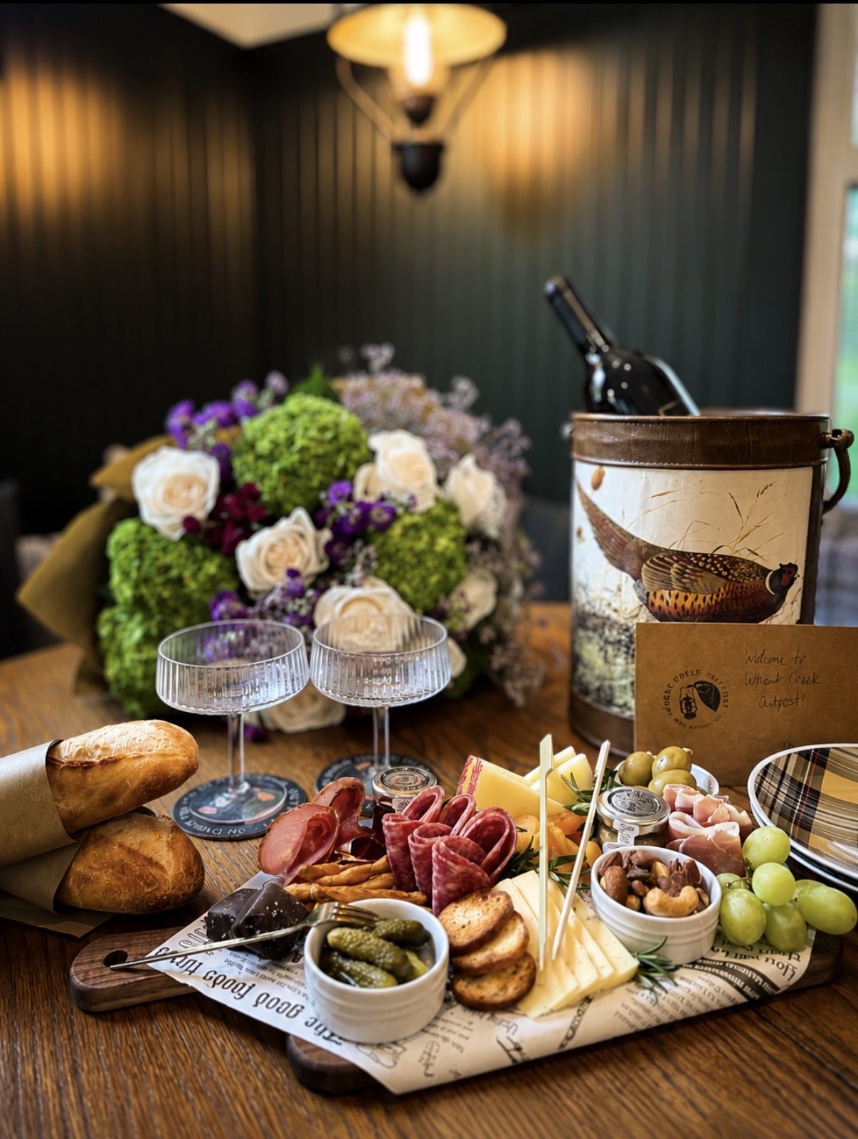 A styled welcome board with wine, glassware, fresh flowers and a handwritten card at a luxury stay